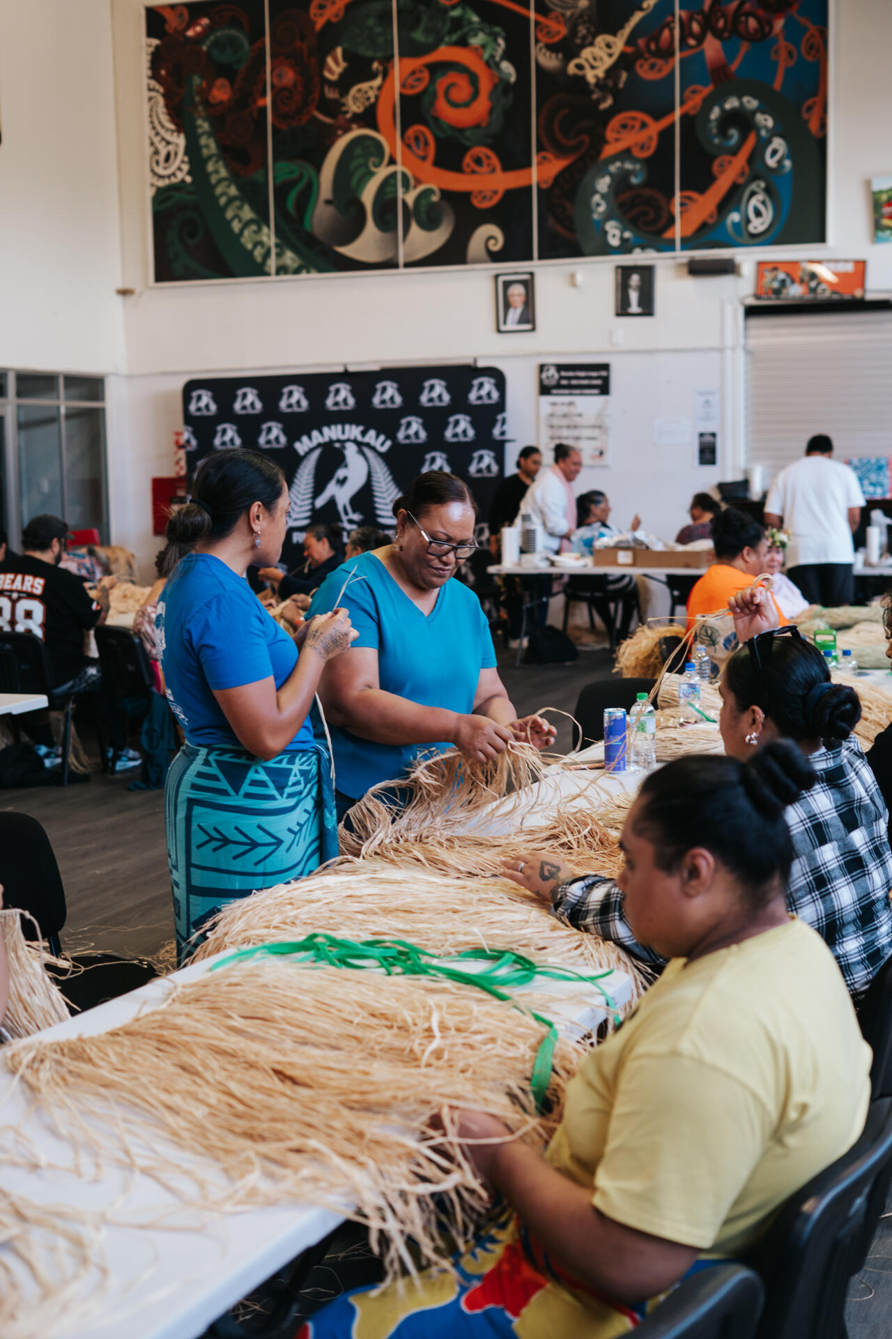 Women in blue weaving together in community hall