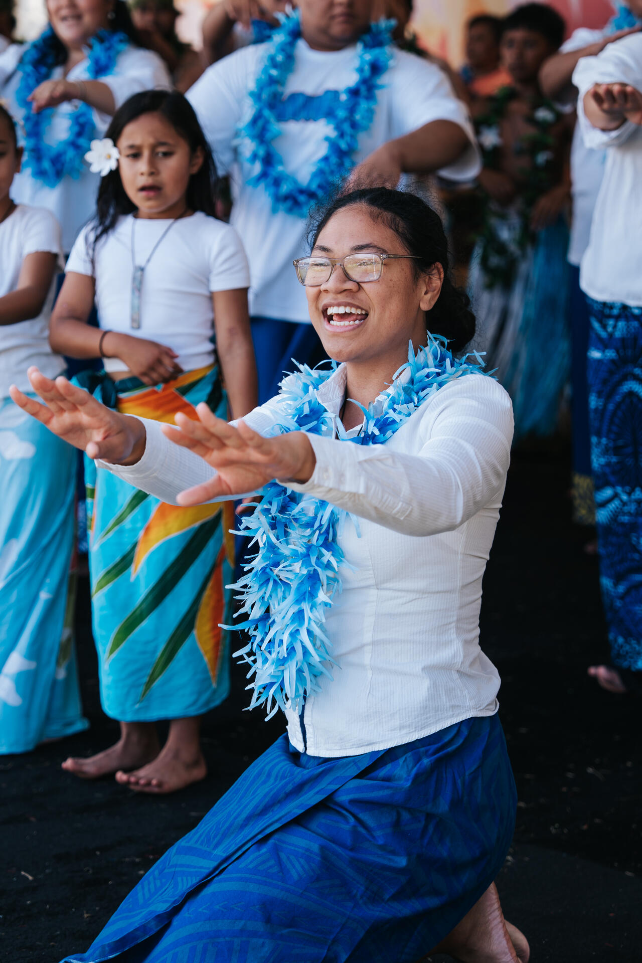 Young woman dancing joyfully in blue lei and lavalava