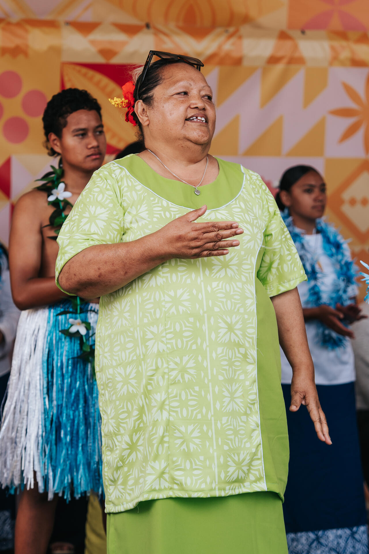 Elder woman singing with hand on heart at cultural performance