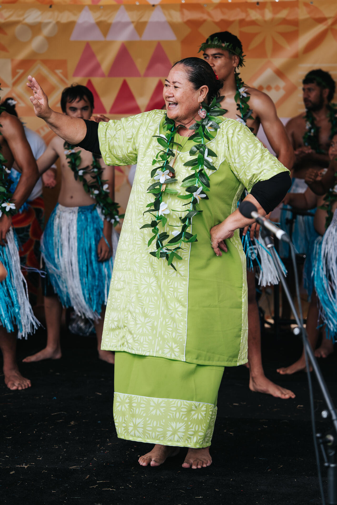 Elder performer with leaf lei dancing joyfully on stage