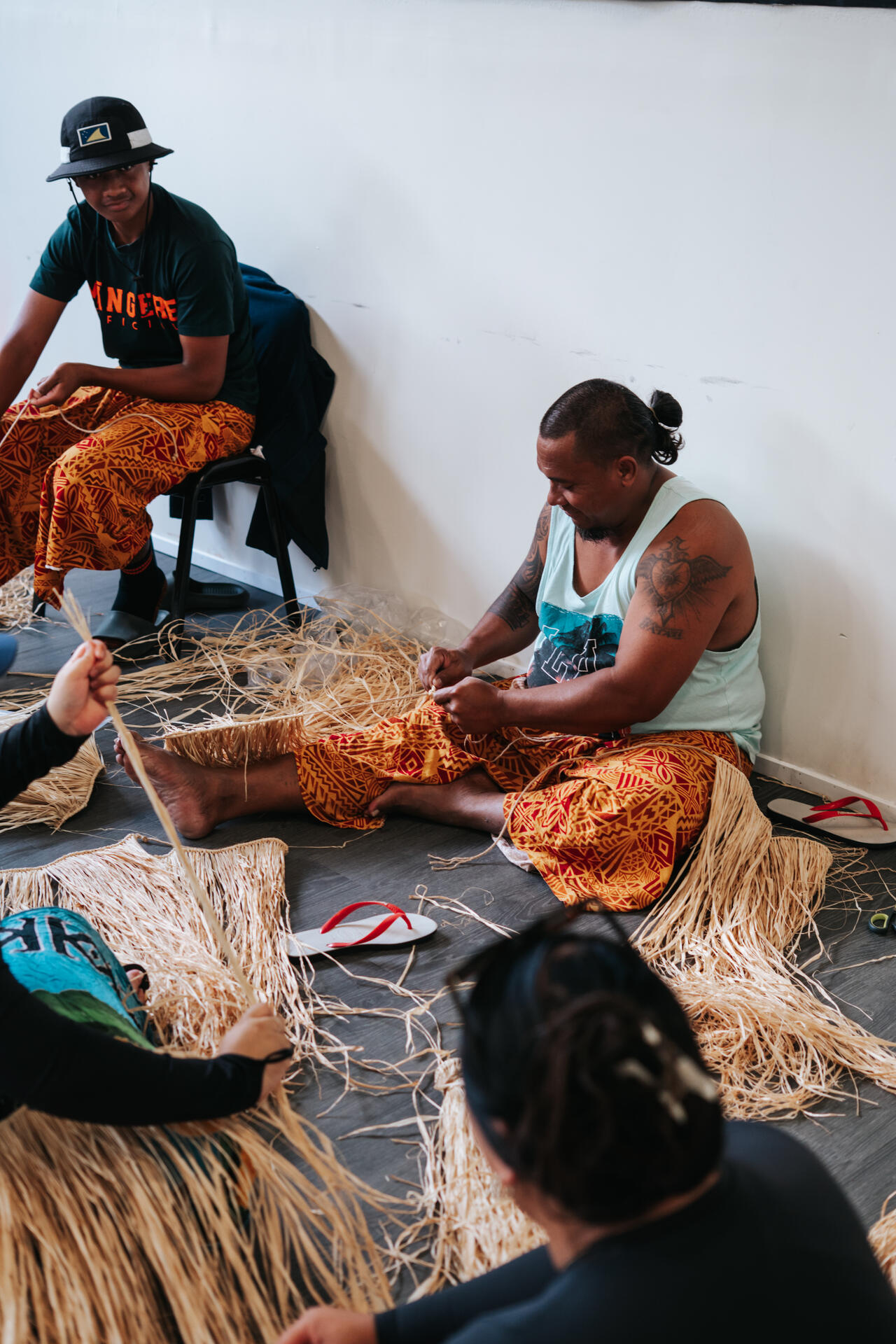 Men weaving traditional skirts on the floor