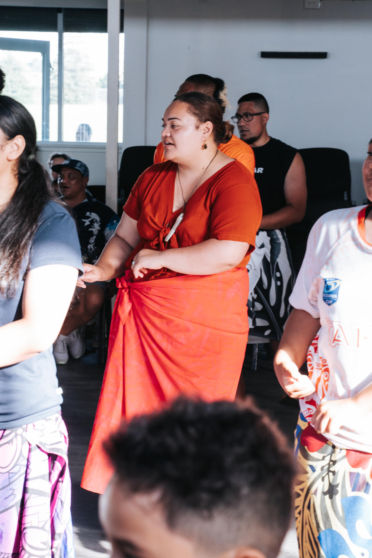 Young woman dancing in orange lavalava at community gathering