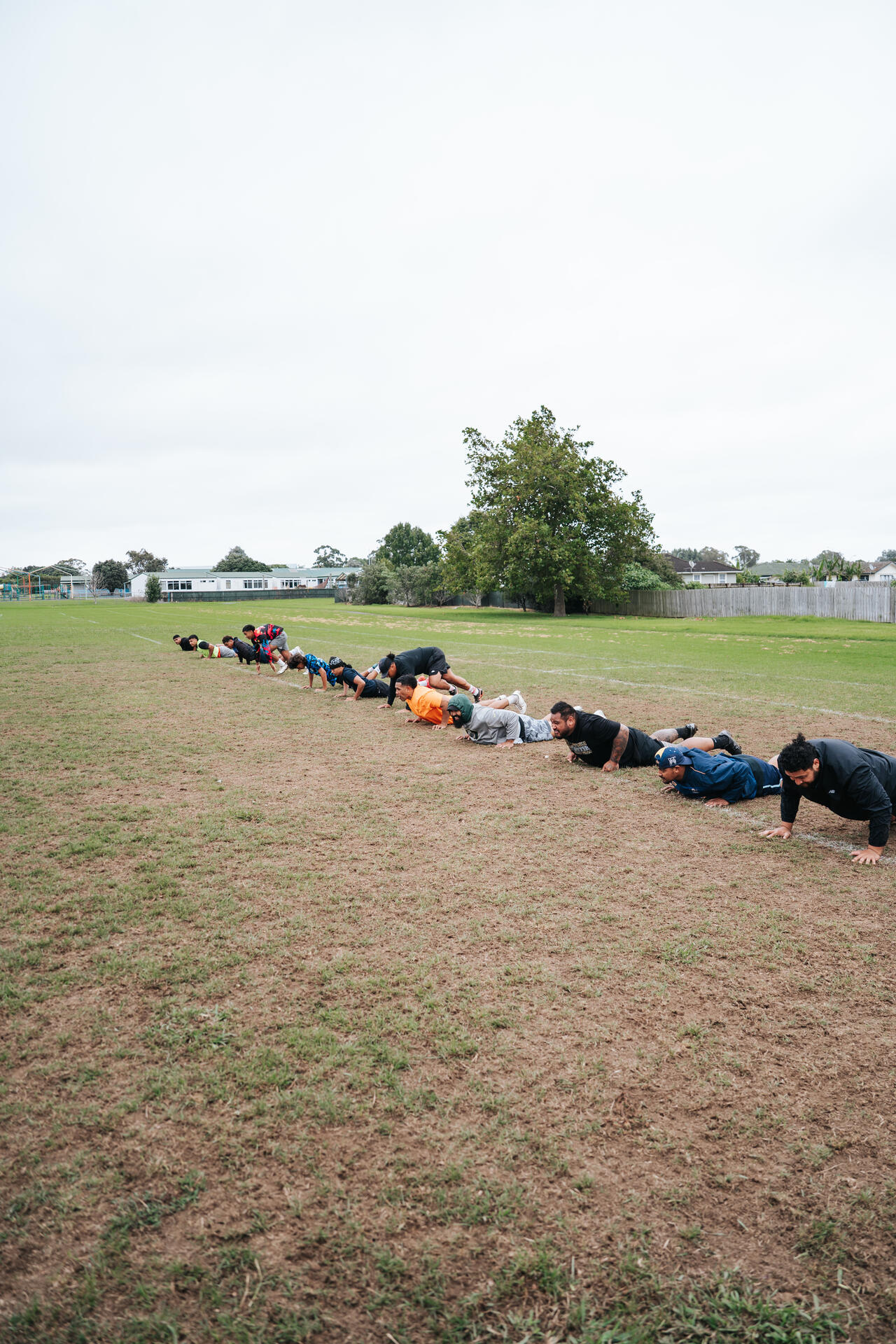 Youth doing pushups in a line on the sports field
