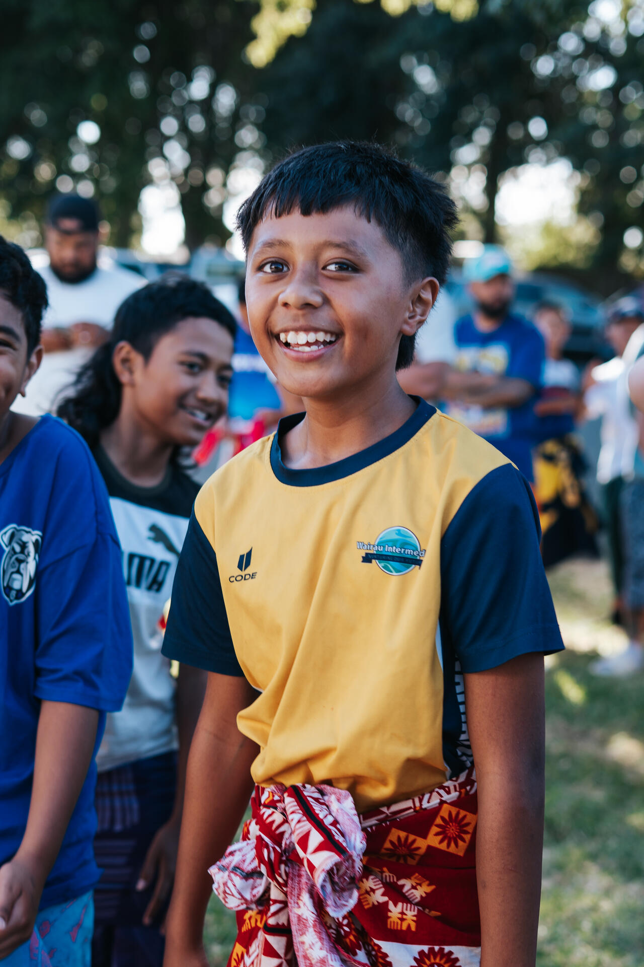 Boy smiling in yellow sports jersey at outdoor event