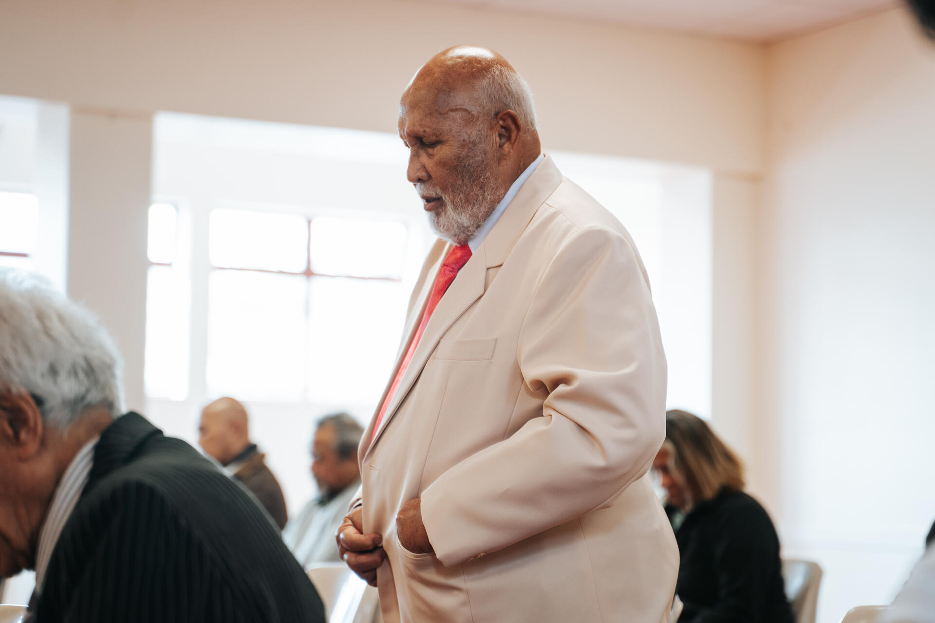 Toeina elder in suit at community meeting