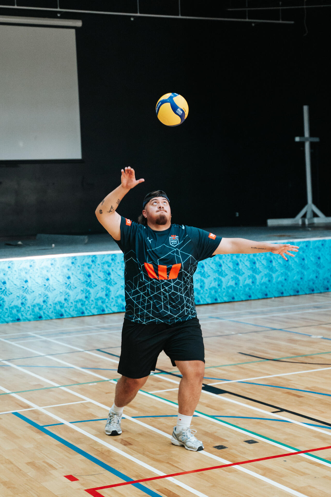 Volleyball player serving with power in indoor court